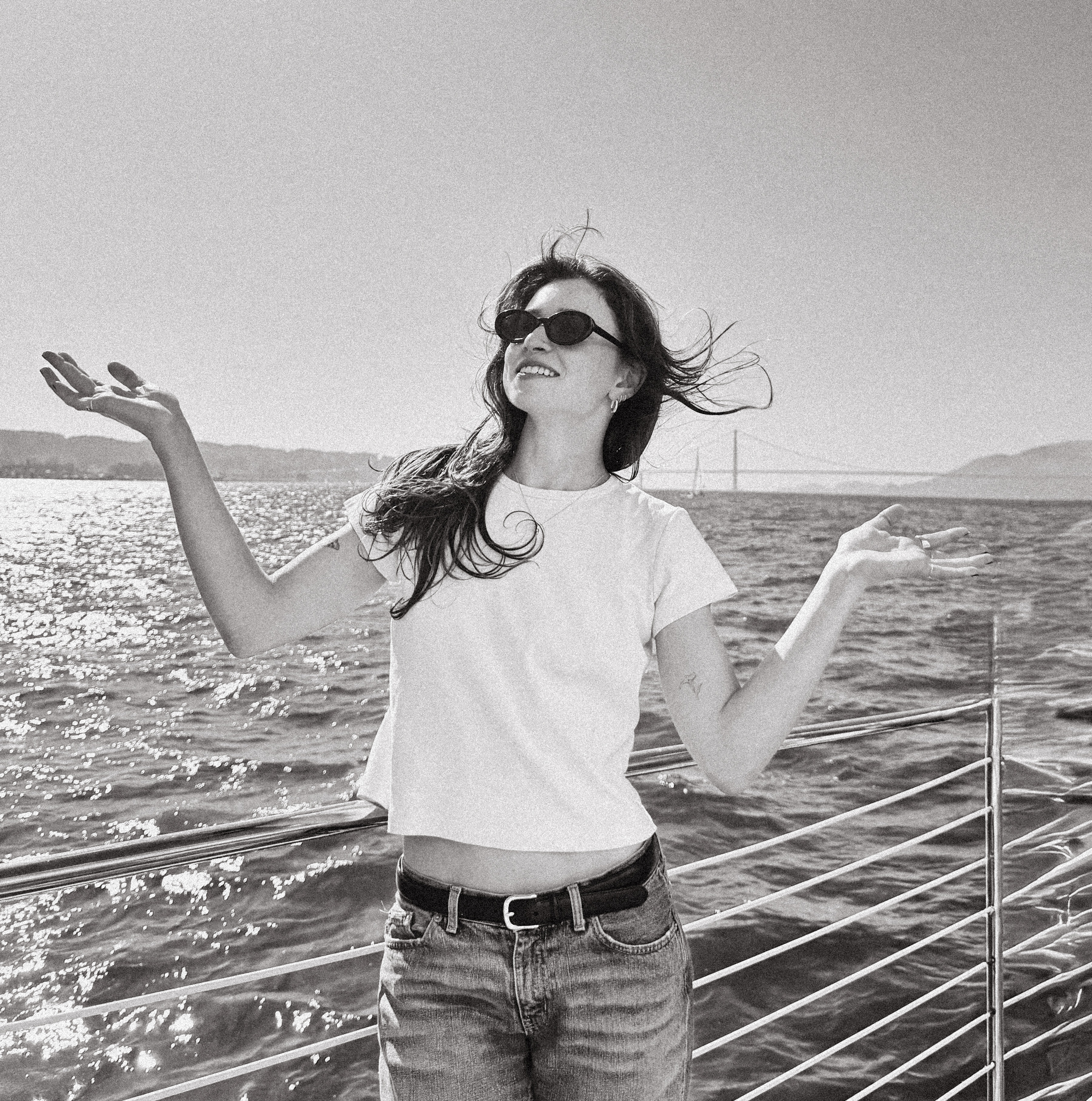 Rachel on a boat, arms raised, laughing