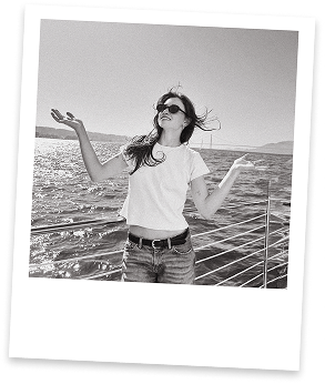 Rachel on a boat, arms raised, laughing